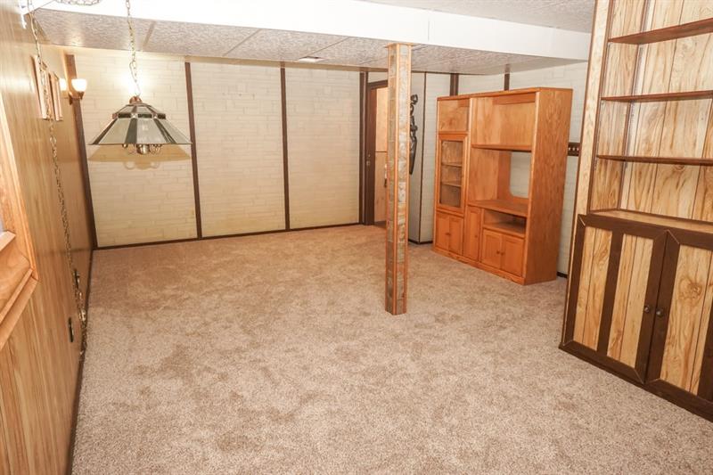223 East Union Road Cheswick, PA 15024 - Photo 18 of 25 Heading Downstairs to the Finished Lower Level Game Room, this would make a great play room, mancave or additional bedroom if needed. Newer carpeting was adding here as well and a Partial Bath is found in the back corner. Built In Shelves for extra storage, this 22x14 (approx) finished space can be utilized in so many ways. Wood Paneling on walls with faux Stone walls along the rear.