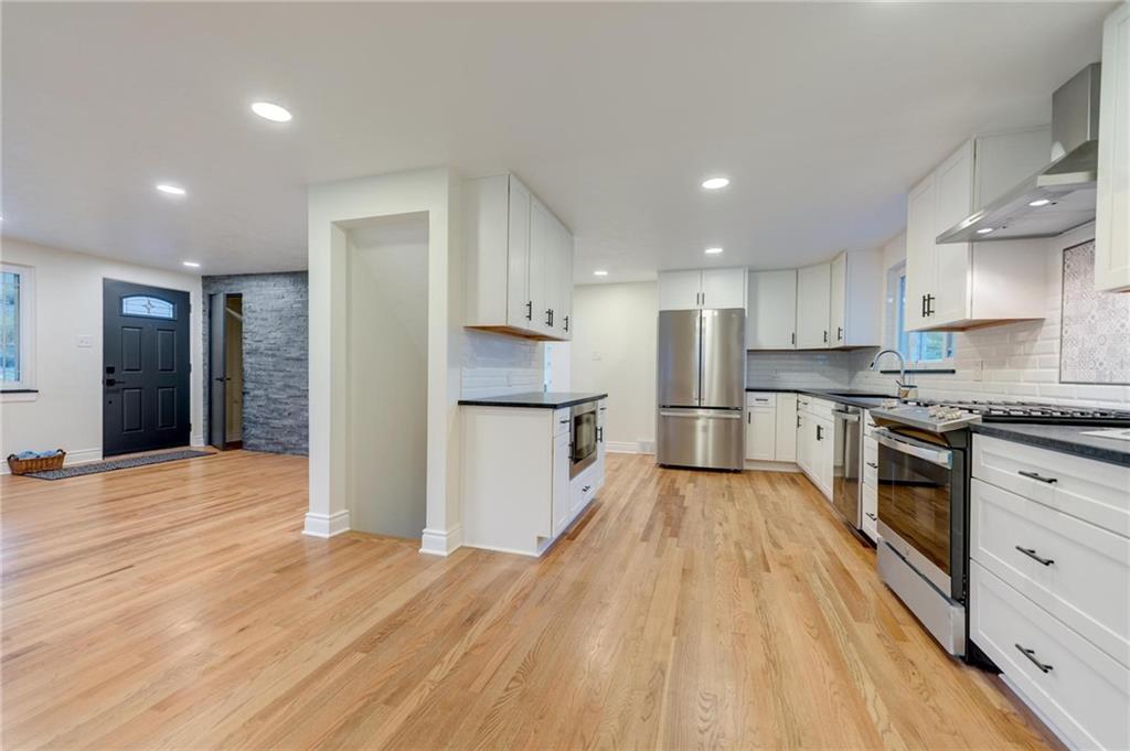 18 Seneca Road Pittsburgh, PA 15241 - Photo 9 of 25 a kitchen with stainless steel appliances granite countertop a refrigerator oven a sink dishwasher and white cabinets with wooden floor