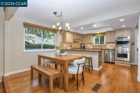 a kitchen with granite countertop a sink stainless steel appliances white cabinets and a window