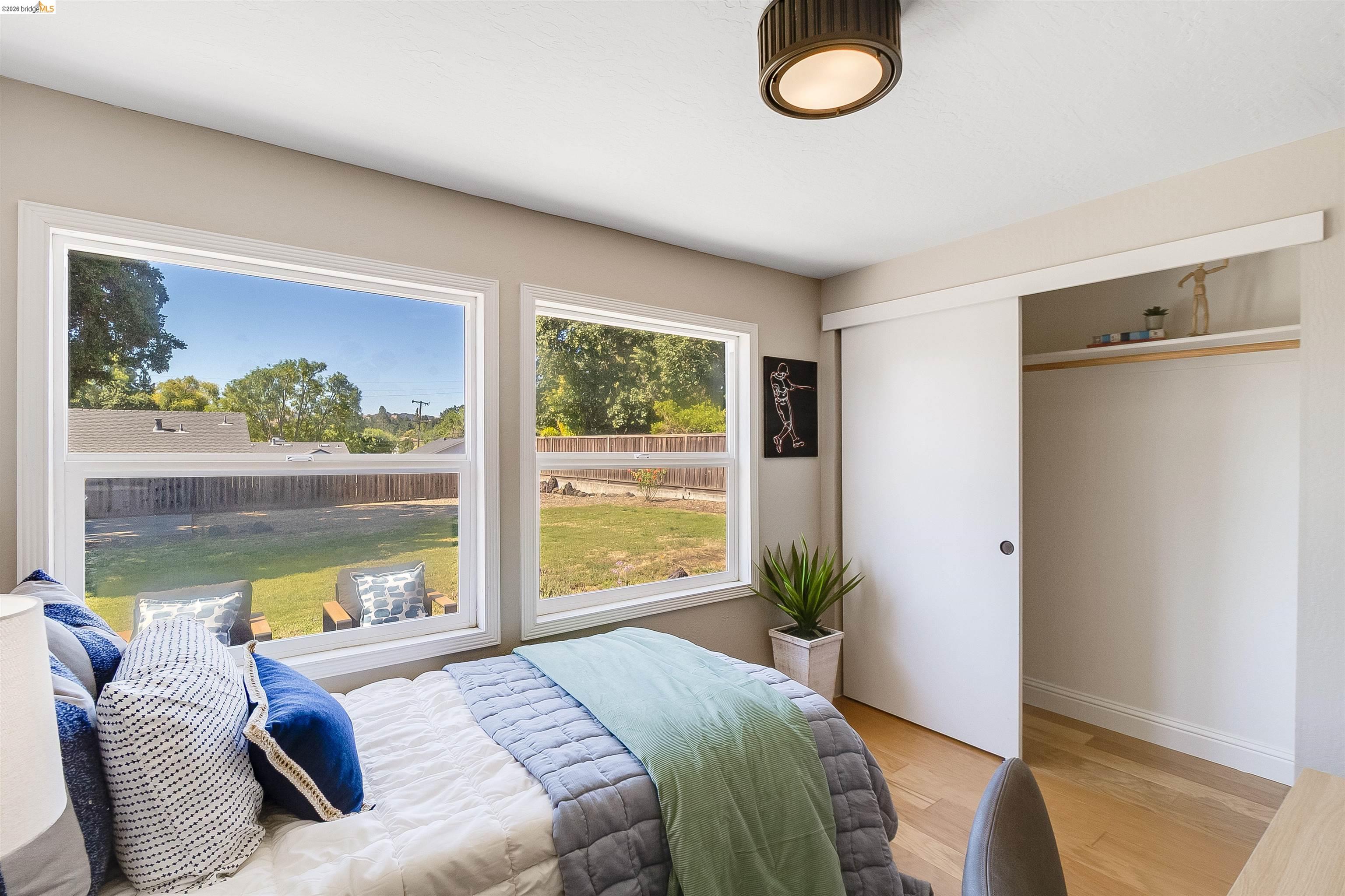 346 Valley View Road Pleasant Hill, CA 94523 - Photo 34 of 57 Bedroom featuring two large windows, sliding closet doors, wood-finish flooring, a contemporary ceiling light fixture, and baseboard molding