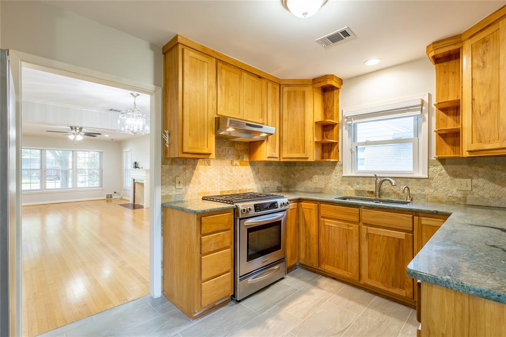 6165 Ravendale Lane Dallas, TX 75214 - Photo 14 of 40 a kitchen with stainless steel appliances granite countertop a sink a stove and a wooden floors