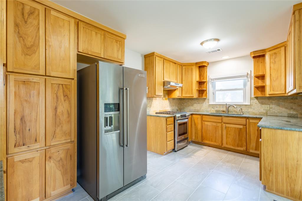 6165 Ravendale Lane Dallas, TX 75214 - Photo 19 of 40 a kitchen with stainless steel appliances granite countertop a refrigerator and a sink