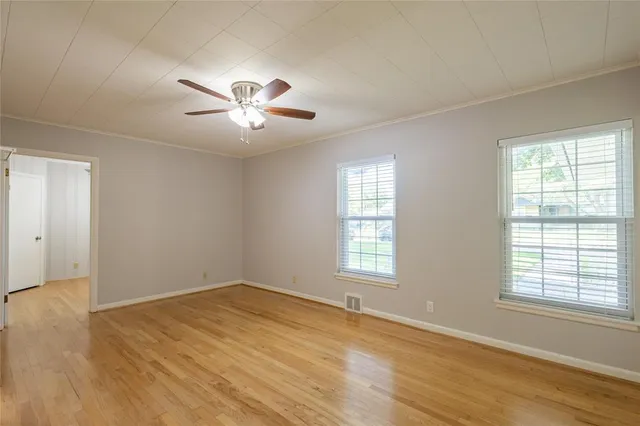 a view of empty room with wooden floor and fan