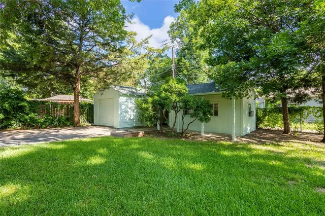 a backyard of a house with table and chairs and a large tree
