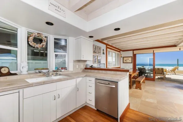 a kitchen with a sink dishwasher a stove and white cabinets with wooden floor