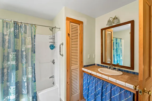 a bathroom with a double vanity sink and mirror with bathtub