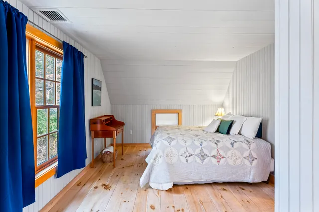 a bedroom with a bed and a large window with wooden floor