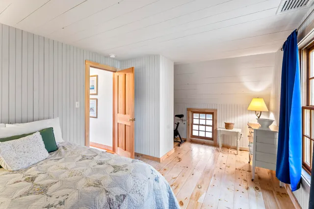 a spacious bedroom with a bed and wooden floor