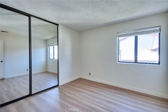 an empty room with wooden floor mirror and windows