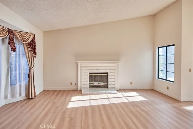 an empty room with windows and fireplace