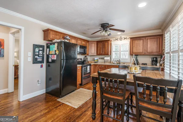 a kitchen with stainless steel appliances granite countertop a refrigerator a stove a sink a dining table and chairs with wooden floor