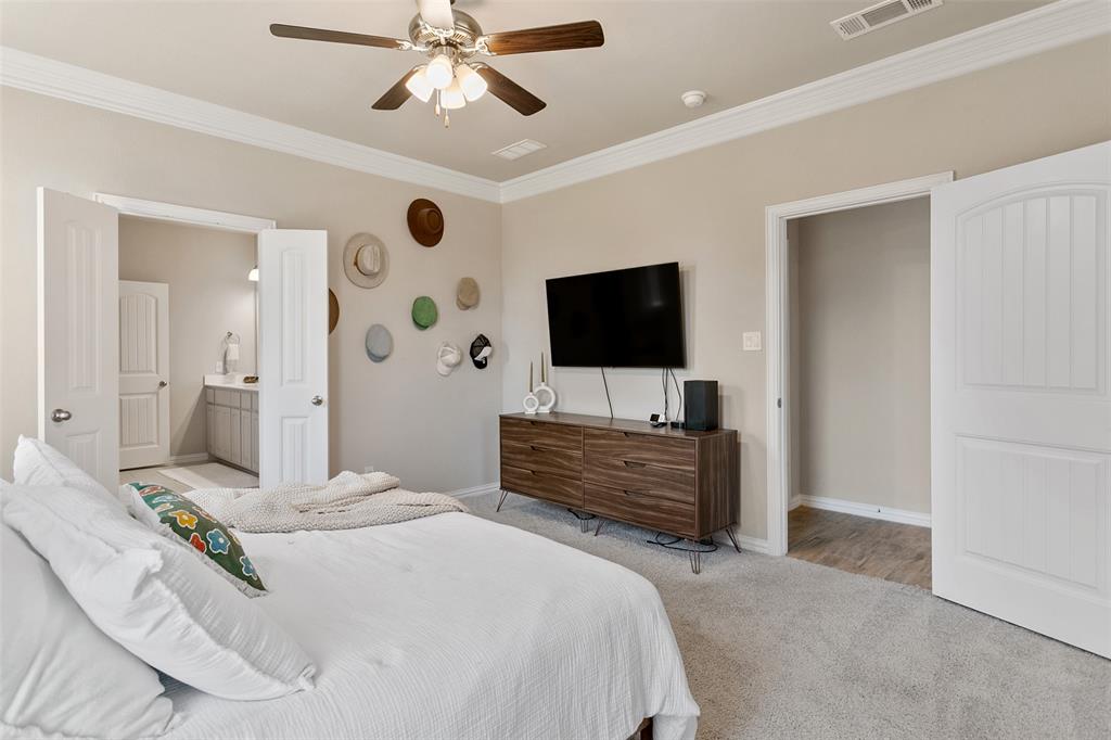 129 Cooper Court Springtown, TX 76082 - Photo 16 of 27 Bedroom featuring light colored carpet, connected bathroom, ceiling fan, and crown molding