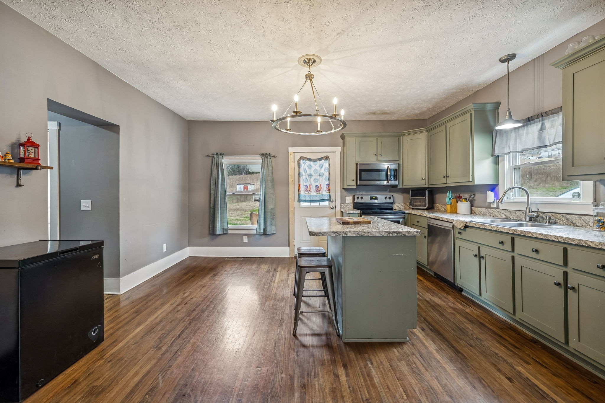 147 Sloan Branch Road Pleasant Shade, TN 37145 - Photo 22 of 53 a kitchen with a refrigerator a sink dishwasher a dining table and chairs with wooden floor