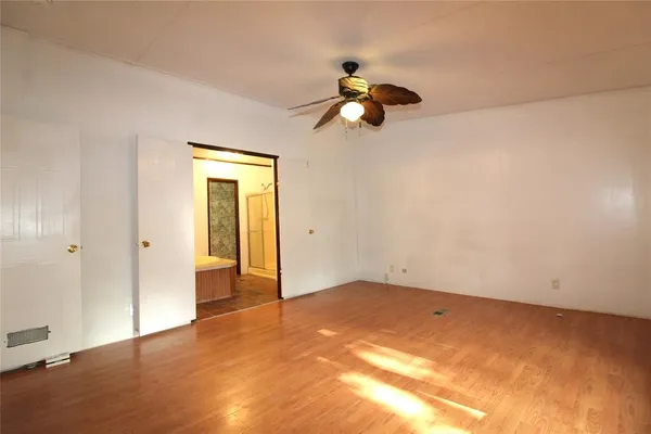 a view of a big room with wooden floor and windows