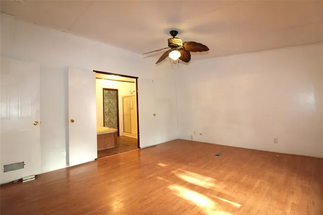 a view of a big room with wooden floor and windows