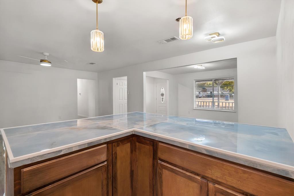 3400 Emhouse Road Corsicana, TX 75110 - Photo 21 of 34 L-shaped counter featuring a patterned surface, wood-finish cabinetry, and overhead pendant lighting