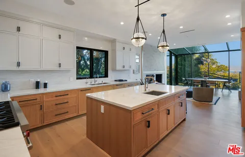 a large kitchen with kitchen island a stove a sink a center island and living room view