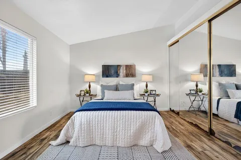 a bedroom with a bed wooden floor and lamp