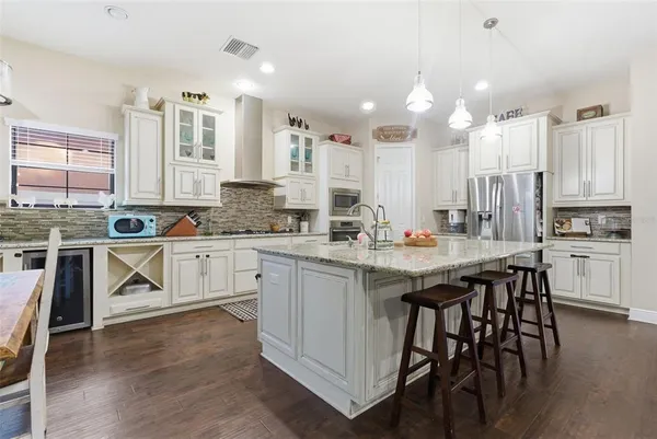 a kitchen with stainless steel appliances kitchen island granite countertop a stove a sink dishwasher and white cabinets with wooden floor