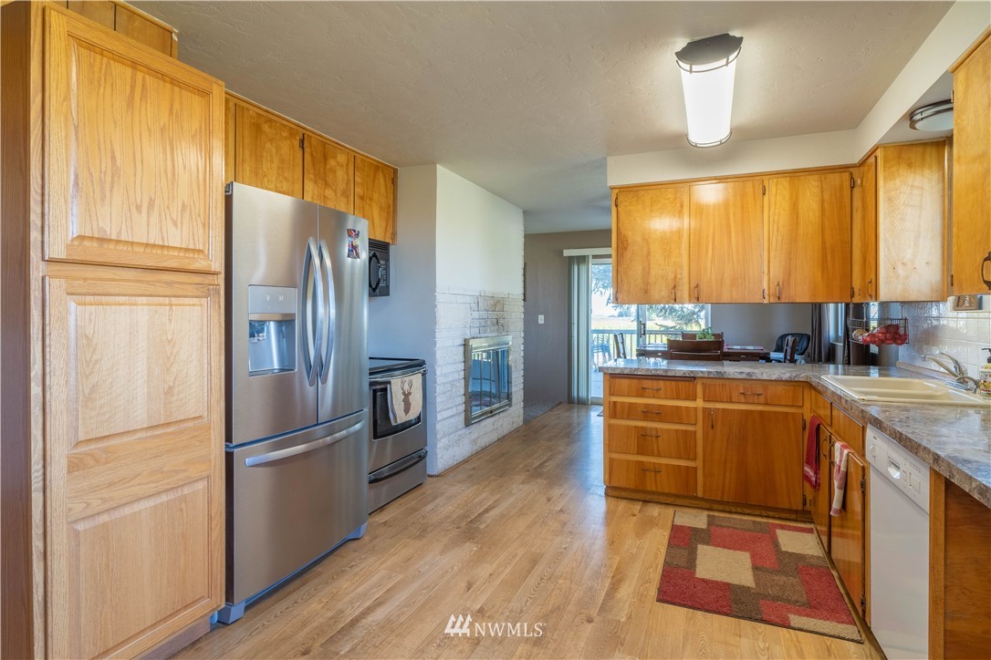 512 Rd P Northeast Moses Lake, WA 98837 - Photo 6 of 39 a kitchen with stainless steel appliances granite countertop a refrigerator a stove a sink dishwasher and wooden cabinets with wooden floor