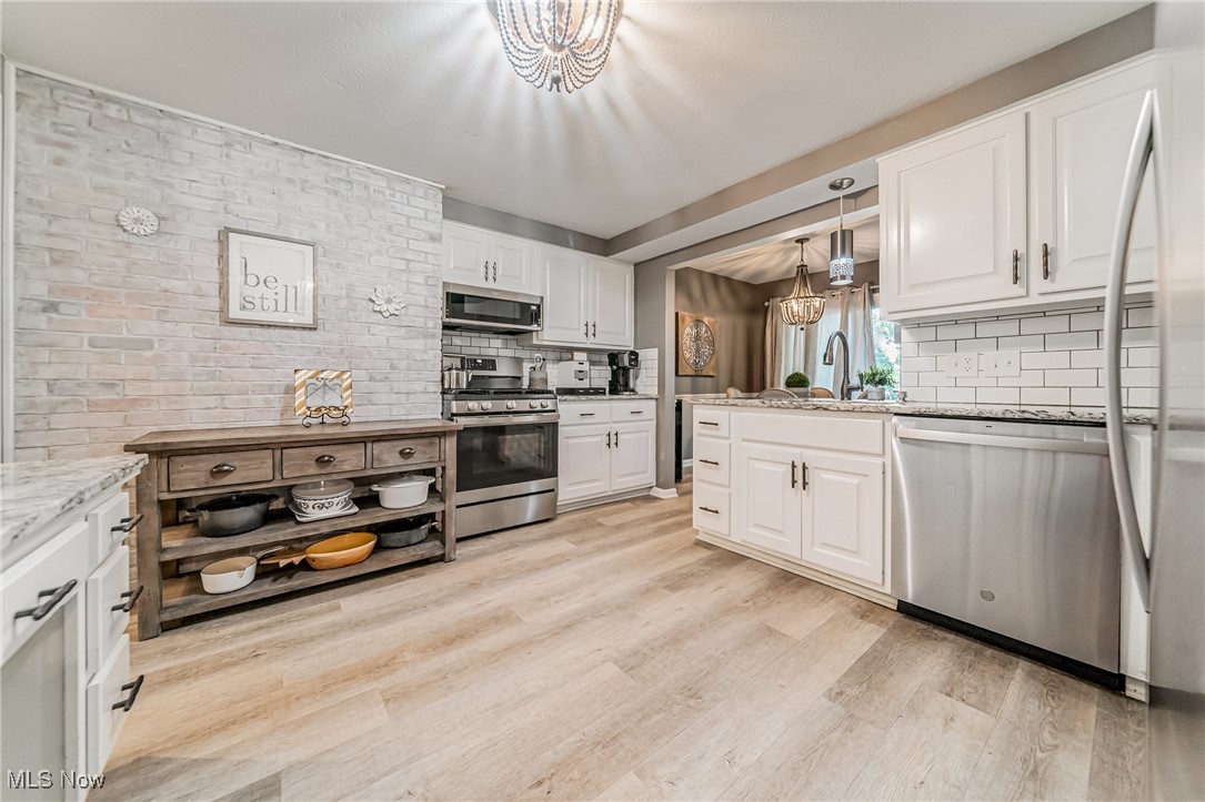 595 Moorfield Road Fairlawn, OH 44313 - Photo 13 of 50 Kitchen with a chandelier, stainless steel appliances, white cabinetry, hanging light fixtures, and light stone counters