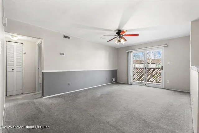 an empty room with chandelier fan and windows