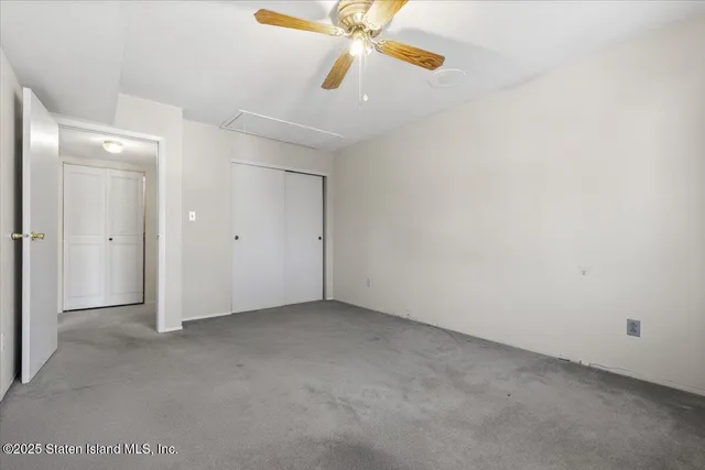 an empty room with closet and a ceiling fan