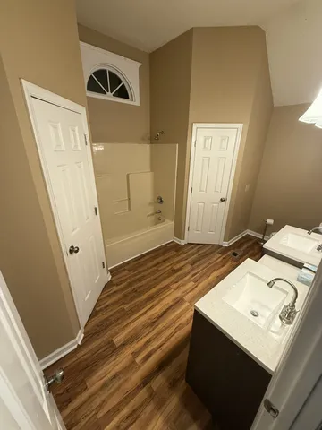a view of a bedroom with wooden floor and white walls