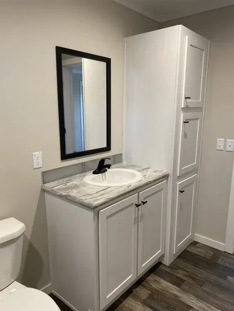 a bathroom with a granite countertop sink toilet and mirror