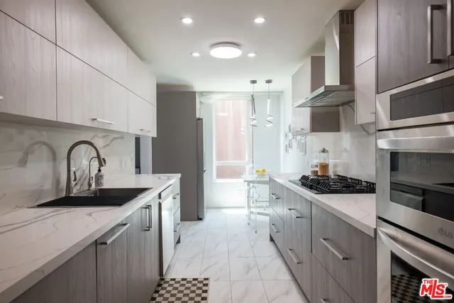 a kitchen with stainless steel appliances granite countertop a sink stove refrigerator and cabinets