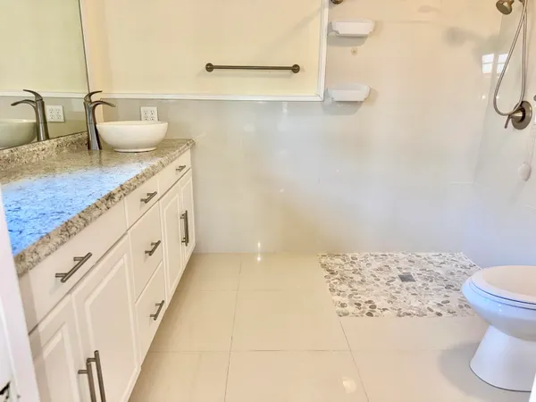 a bathroom with a granite countertop sink a toilet and mirror