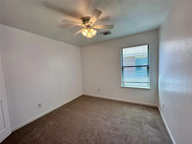 an empty room with windows and chandelier fan