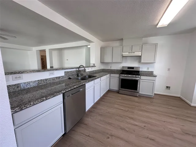 a kitchen with stainless steel appliances granite countertop wooden cabinets a granite counter tops and a hard wood floors