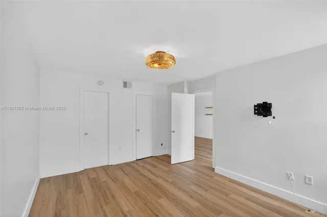 a view of an empty room with wooden floor and window