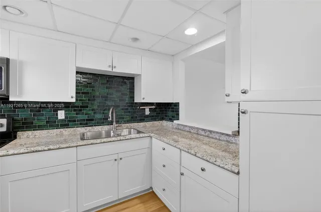 a kitchen with granite countertop white cabinets and white appliances