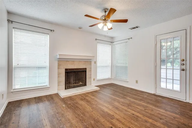 a view of an empty room with wooden floor fireplace and a window