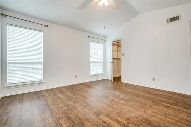 an empty room with wooden floor and windows
