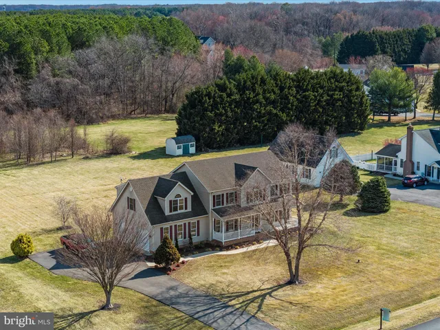 a front view of a house with a yard covered with snow and trees