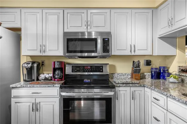 a kitchen with granite countertop white cabinets and appliances