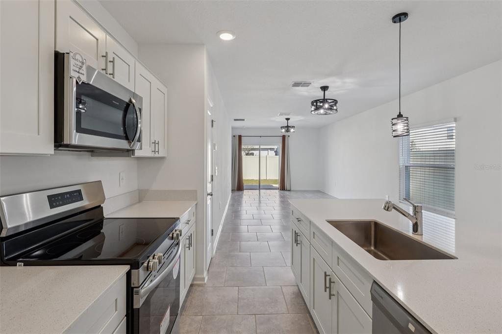 1723 Foreman Road Eagle Lake, FL 33839 - Photo 15 of 34 a kitchen with stainless steel appliances granite countertop a sink a stove and a microwave oven with white cabinets
