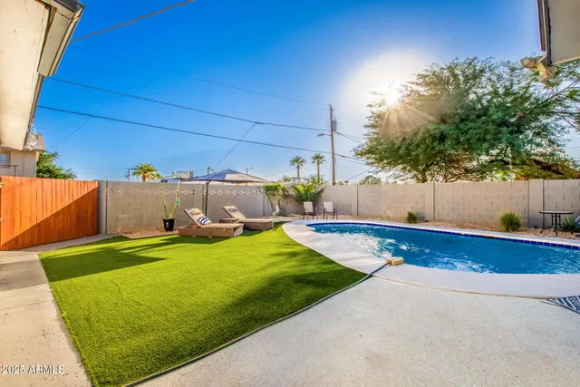 a view of swimming pool with lawn chairs under an umbrella