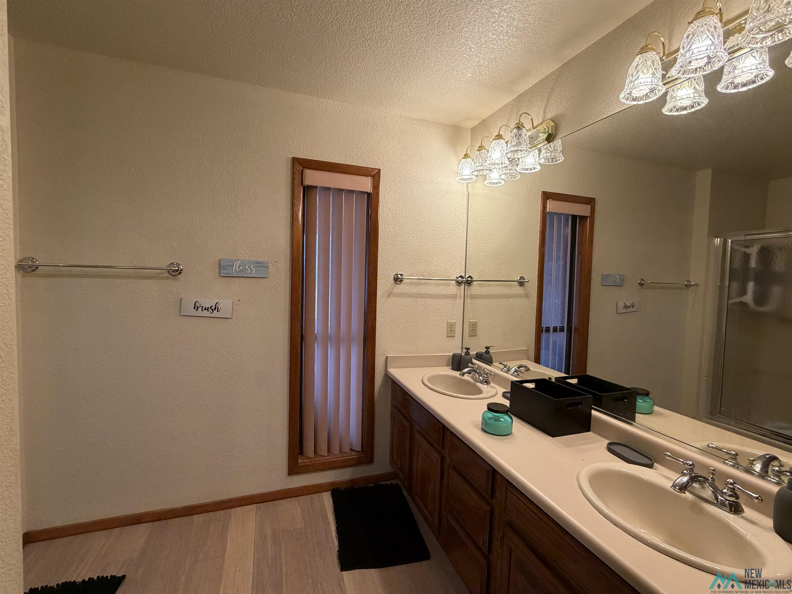 2001 East Derrick Road Carlsbad, NM 88220 - Photo 66 of 84 Bathroom with double vanity, a textured wall, light wood finished floors, an enclosed shower, and a textured ceiling
