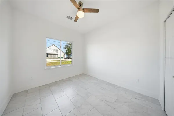 an empty room with windows and ceiling fan