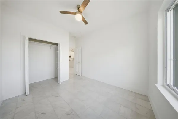 an empty room with ceiling fan and window