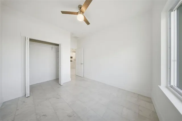 an empty room with ceiling fan and window