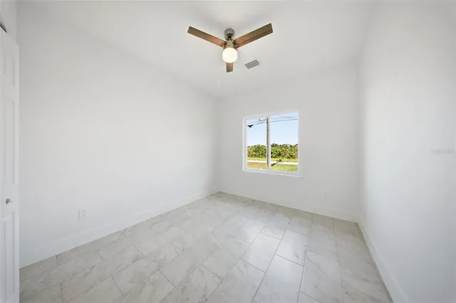 an empty room with a window and a ceiling fan