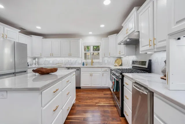 a kitchen with stainless steel appliances granite countertop a sink stove refrigerator and cabinets