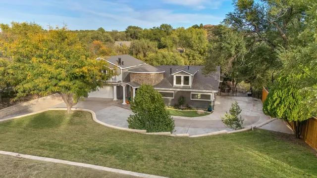 an aerial view of a house with a yard and a large tree