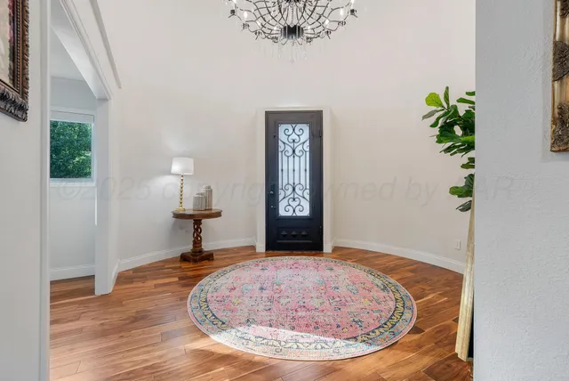 a view of a hallway with wooden floor and a potted plant