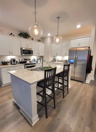 a kitchen with kitchen island a dining table chairs and white cabinets